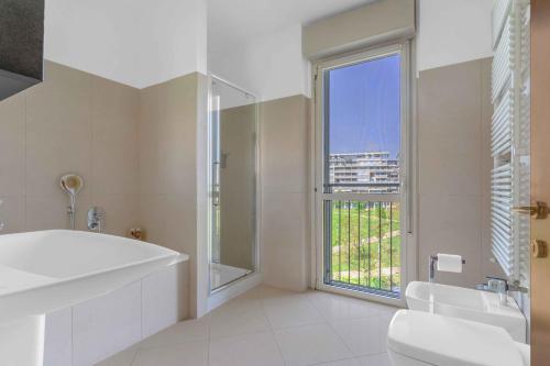 ein Bad mit einer Badewanne, einem Waschbecken und einem Fenster in der Unterkunft Santa Giulia Suite - Futurismo 17 in Mailand