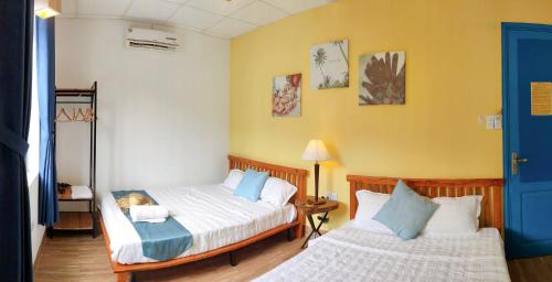 two beds in a room with yellow walls at Sunbay Homestay Cu Lao Cham in Tân Hiệp