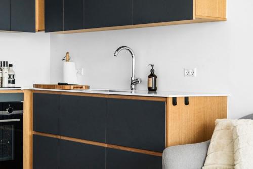 a kitchen with black and white cabinets and a sink at Above the clouds on 42nd floor in Aarhus