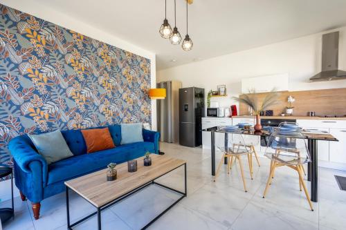 ein Wohnzimmer mit einem blauen Sofa und einer Küche in der Unterkunft Le Séquoia - Maison neuve climatisée in Saix