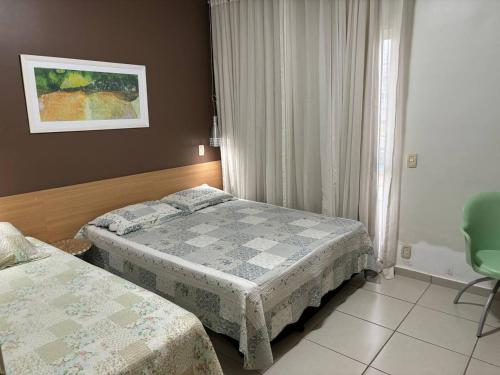 une chambre d'hôtel avec deux lits et une chaise dans l'établissement Apartamento Village Aldeia das Águas, à Barra do Piraí