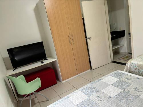 - une chambre avec un lit, une télévision et une chaise verte dans l'établissement Apartamento Village Aldeia das Águas, à Barra do Piraí