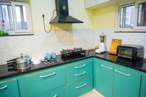 a kitchen with blue cabinets and a stove top oven at Casa Feliz @ Near US Embassy , Gachibowli in Hyderabad
