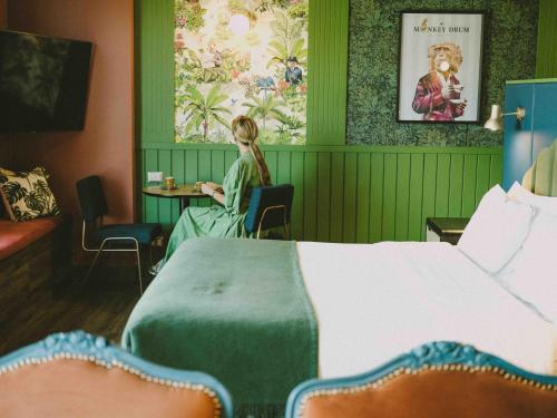 uma menina sentada numa mesa num quarto de hotel em Hotel Eco Boutique Bidasoa em Santiago