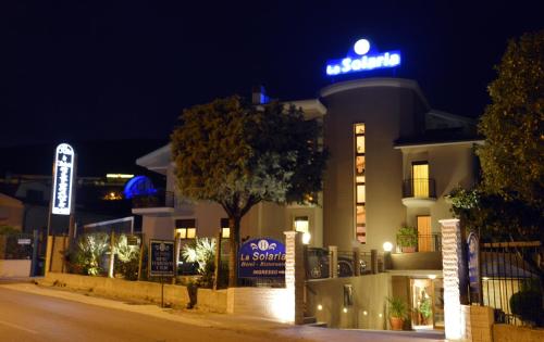 a building with a neon sign on top of it at Hotel e Appartamenti La Solaria con parcheggio gratuito a soli 450 MT dalla nuova Basilica di Padre Pio in San Giovanni Rotondo