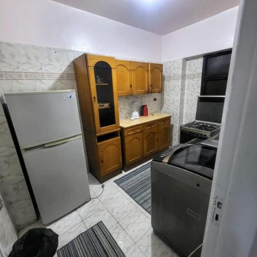 a kitchen with a white refrigerator and wooden cabinets at شقه فى ميامى بالاسكندريه مطله على البحر in Alexandria
