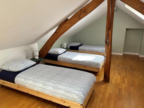 three beds in a attic room with wooden beams at Chez Myriam in Orgeval