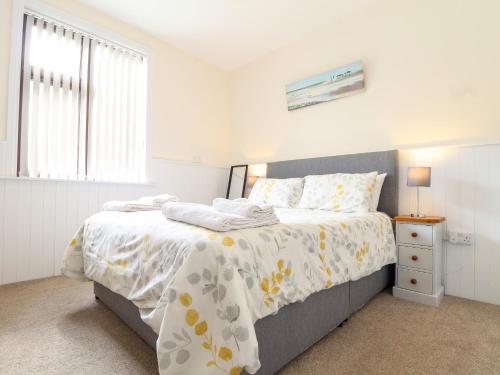 a bedroom with a bed with a white and yellow bedspread at Flat 1 Niles Place in Padstow