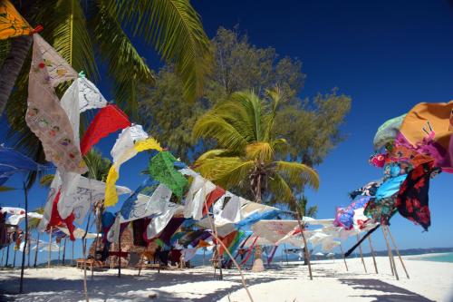 a beach with a bunch of flags and palm trees at Hotel Mahita Tsara in Djamandjary