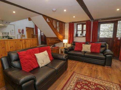 a living room with two leather couches and red pillows at Graig Las The Barn in Oswestry