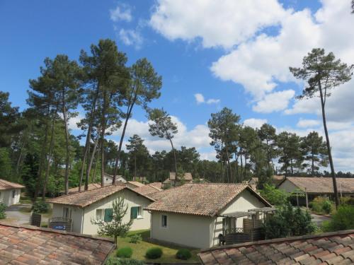 a row of houses with trees in the background at Résidence Goélia Les Demeures du Lac in Casteljaloux
