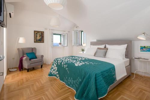 a bedroom with a bed with a green blanket and a chair at Luxury Villa Murvica with private pool near the beach in Murvica on Brac island in Murvica
