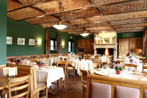 a restaurant with white tables and chairs and a fireplace at La Chartreuse Du Val Saint Esprit in Gosnay