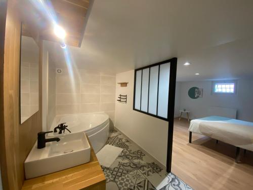 ein Bad mit einer Badewanne, einem Waschbecken und einem Bett in der Unterkunft La P'tite Loupiote in La Loupe