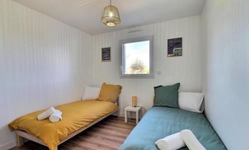 une chambre avec deux lits et une fenêtre dans l'établissement Maison bord de mer avec Jacuzzi, à Penmarcʼh