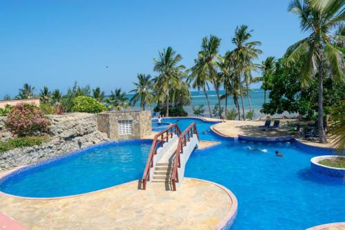 a pool with stairs in a resort with palm trees at La Mera Beachfront Apartment in Mombasa