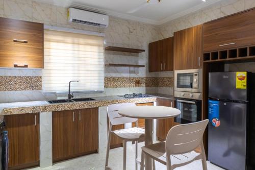 a kitchen with wooden cabinets and a table and chairs at THE OPULENT OASIS in Accra