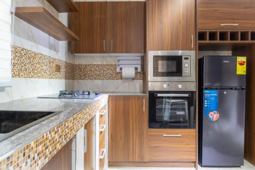a kitchen with wooden cabinets and a stainless steel refrigerator at THE OPULENT OASIS in Accra