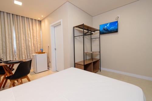 1 dormitorio con cama, escritorio y mesa en Pousada Kauai SFS, en São Francisco do Sul