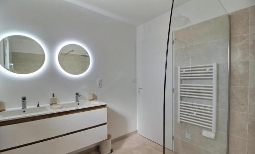 une salle de bain avec un lavabo et deux miroirs dans l'établissement Maison bord de mer avec Jacuzzi, à Penmarcʼh