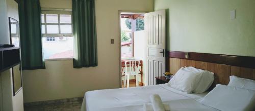 1 dormitorio con cama blanca y ventana en Pousada Arco Iris Ilhéus, en Ilhéus