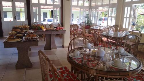 un restaurante con mesas y sillas con comida. en Pousada Arco Iris Ilhéus, en Ilhéus