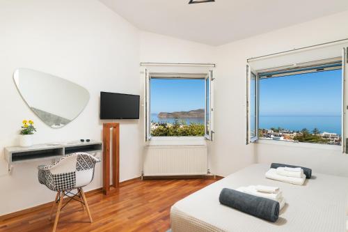 a room with a bed and a chair and two windows at Seaview Garden Villa - Heated Pool & Sauna in Stalos