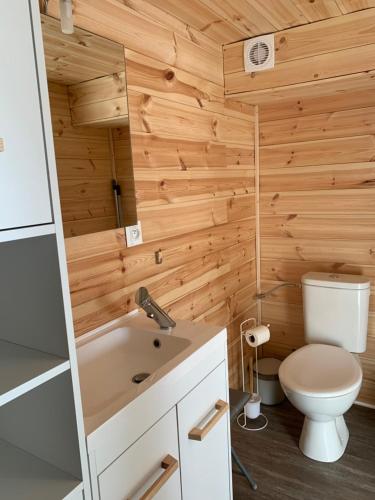a bathroom with wooden walls and a toilet and a sink at Eco-Lodge de Cëuse in Sigoyer