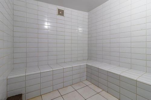 ein Bad mit weiß gefliesten Wänden und einer Dusche in der Unterkunft Loft mobiliado no centro de Blumenau in Blumenau