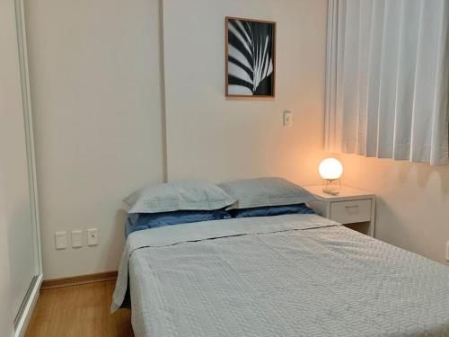 ein Schlafzimmer mit einem Bett und einer Lampe auf einem Tisch in der Unterkunft Loft mobiliado no centro de Blumenau in Blumenau