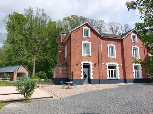 a large red brick house with a white door at Gîte à la campagne in Ghissignies