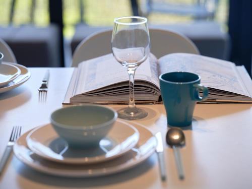 a table with a glass of wine and a book at Najpiękniejszy Bezpośredni Widok na Bałtyk - Twój Apartament in Sarbinowo