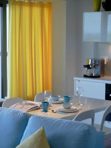 a dining room table with two glasses and a blue couch at Najpiękniejszy Bezpośredni Widok na Bałtyk - Twój Apartament in Sarbinowo
