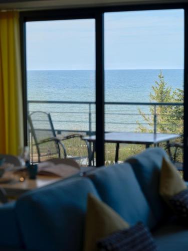 a view of the ocean from a room with a couch at Najpiękniejszy Bezpośredni Widok na Bałtyk - Twój Apartament in Sarbinowo