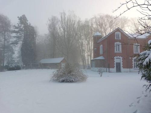 a red brick house with snow in front of it at Gîte à la campagne in Ghissignies