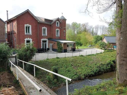 a red brick house with a bridge next to a river at Gîte à la campagne in Ghissignies