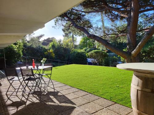 a patio with a table and chairs and a lawn at Villa Kerjoa - T8 - grand jardin in Arcachon