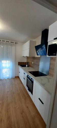 une cuisine avec des appareils blancs et un parquet dans l'établissement Nouvel Appartement à 10mn à pied du Centre-Ville, à Albi