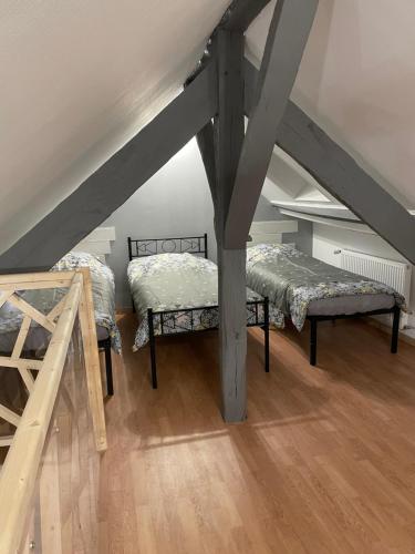 Cette chambre mansardée comprend deux lits et un escalier. dans l'établissement Gîte o prés de la Loire, à Ousson-sur-Loire