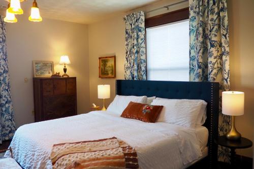 a bedroom with a large bed with blue curtains and a window at Firefly Hills in Beattyville