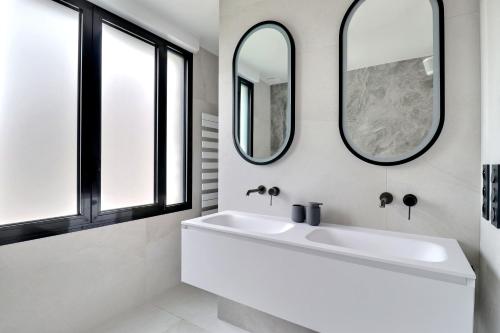 a bathroom with a white sink and two mirrors at Belle maison avec piscine à 30 min de Paris in Yerres