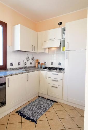 a kitchen with white cabinets and a sink at Relax Home in La Caletta