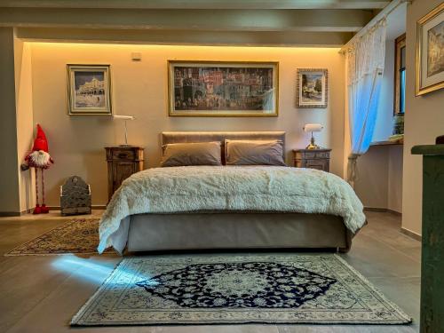 a bedroom with a large bed and a rug at Le Bourg Charmant - Fleur du Printemps in Arvier
