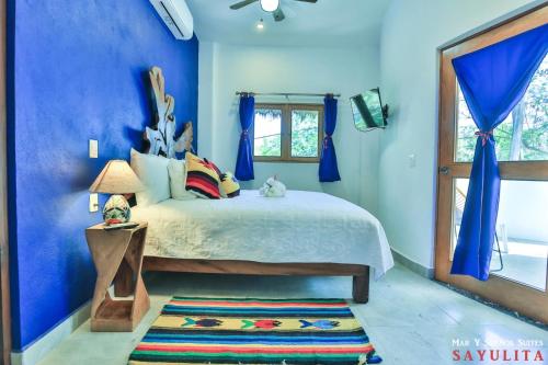 Dormitorio azul con cama y ventana en Mar y Sueños Suites en Sayulita