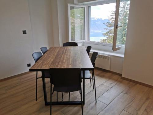 a dining room table with chairs and a large window at Résidence Alpina Caux in Montreux