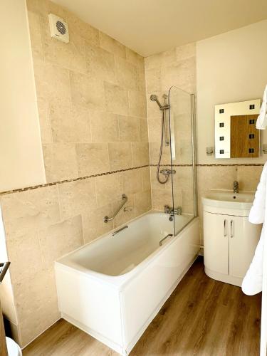 クリクキエスにあるCaerwylan Hotelの浴槽、シャワー、洗面台を備えたバスルーム