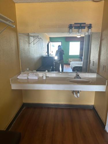 a person taking a picture of a bathroom with a sink at AMERICAN INN in Sumter