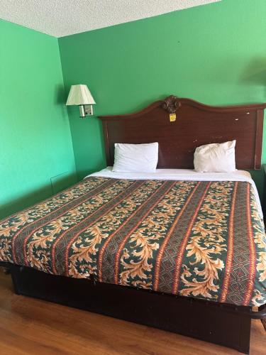 a bed in a room with a green wall at AMERICAN INN in Sumter