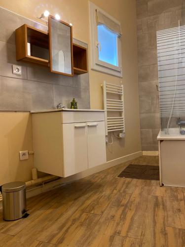 une cuisine avec des armoires blanches, un évier et une fenêtre dans l'établissement Appartement coeur centre ville, à Noyon