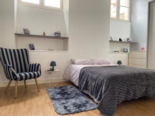 une chambre avec un lit et une chaise dans l'établissement Appartement coeur centre ville, à Noyon